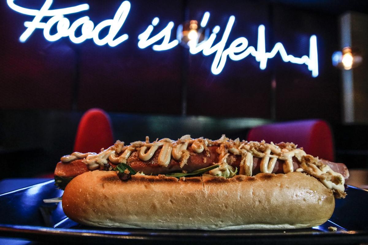 Un perrito caliente sobre el neón con el eslogan de Devora Fast&amp;Good