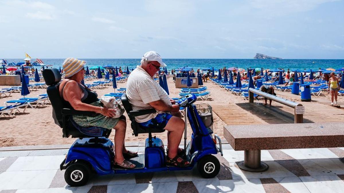 Dos abuelos pasean sobre un carro de discapacitados convertido en el vehículo favorito de la tercera edad.