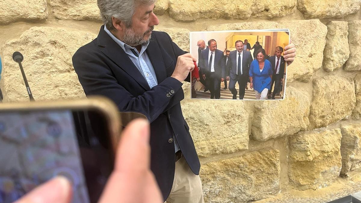 El portavoz del PP, Miguel Ángel Torrico, sostiene una imagen de la visita de Ábalos al Ayuntamiento de Córdoba siendo alcaldesa Isabel Ambrosio.