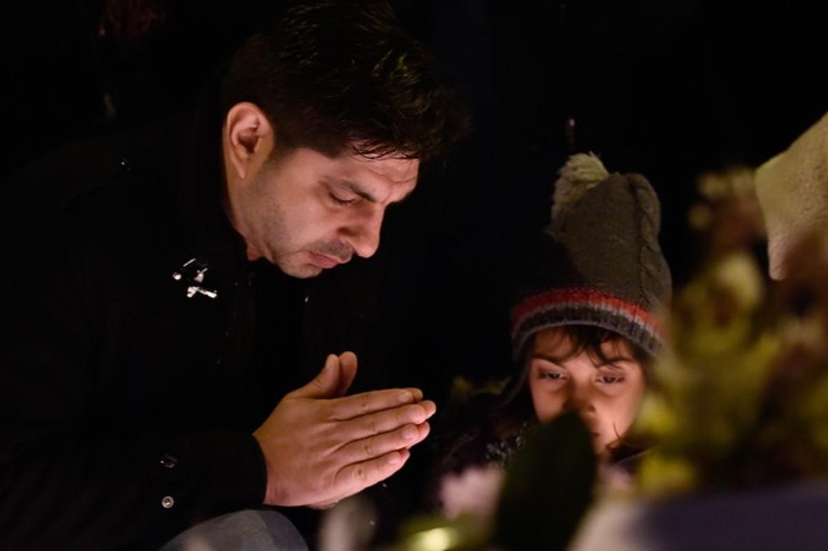 Un hombre y su hijo rezan ante uno de los altares de flores y velas en París.