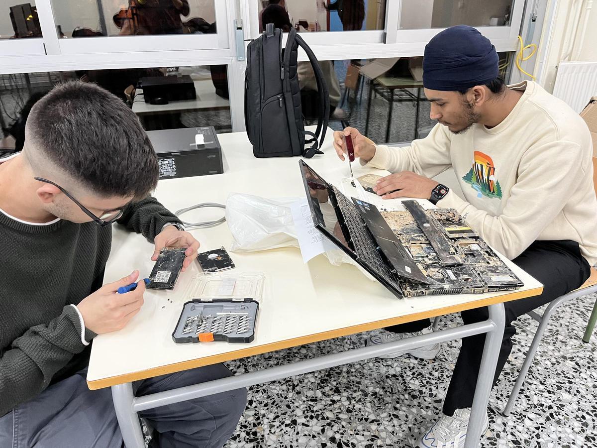Dos alumnos del instituto vallero reparando equipos informáticos llegados de la zona cero.