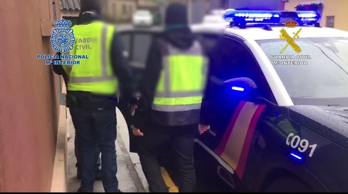 Uno de los detenidos es conducido al interior de un coche de la Policía Nacional.