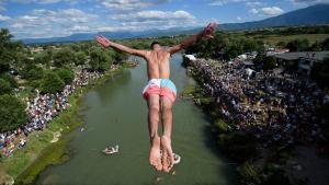 Un buzo salta desde el puente de 22 metros de altura Ura e Shenjte, como señal de protesta después de que la policía cancelara la 70ª competencia anual tradicional de buceo de altura en el puente, cerca de la ciudad de Gjakov.