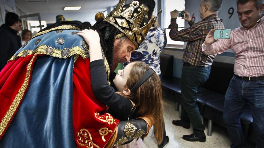 Una niña se abraza al rey Melchor en la planta infantil del Hospital