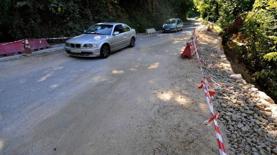 Dos coches pasan por la zona de La Foz, donde se arregla un hundimiento en la vía.