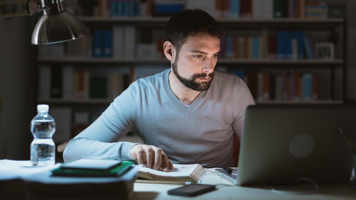 Un joven estudia mientras utiliza un ordenador.