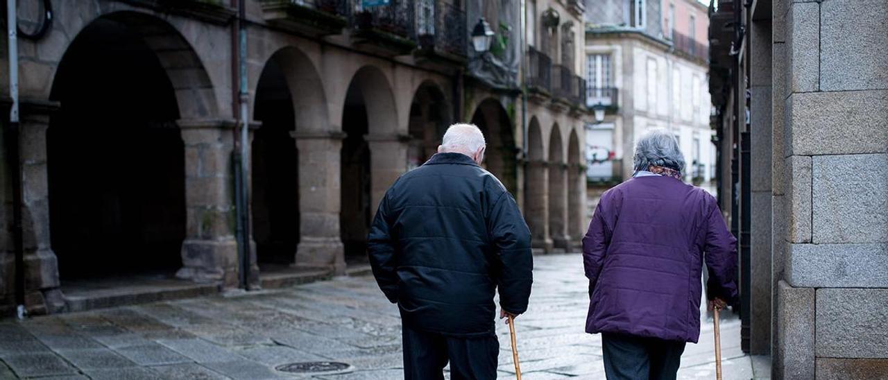 Una pareja de personas mayores pasea por las calles de Ourense