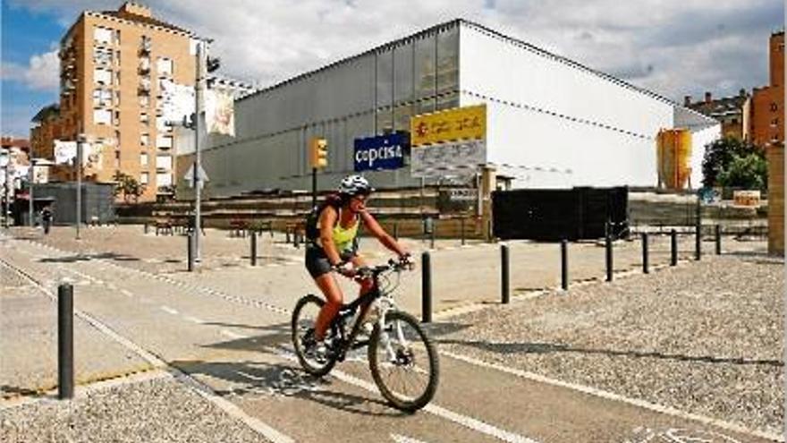 Una ciclista passa per davant de la biblioteca, encara en obres, del carrer Emili Grahit.