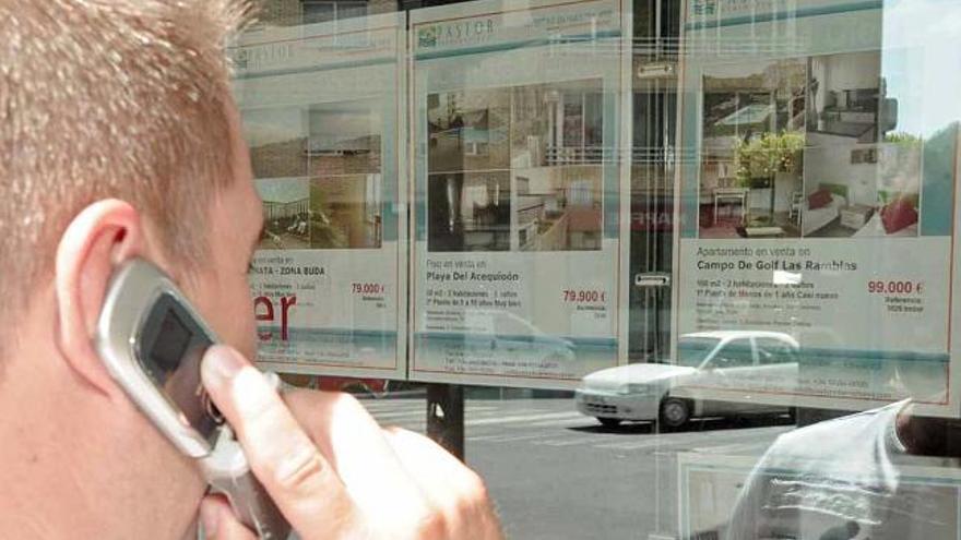 Un cliente potencial observa las ofertas expuestas en el escaparate de una agencia inmobiliaria de Torrevieja