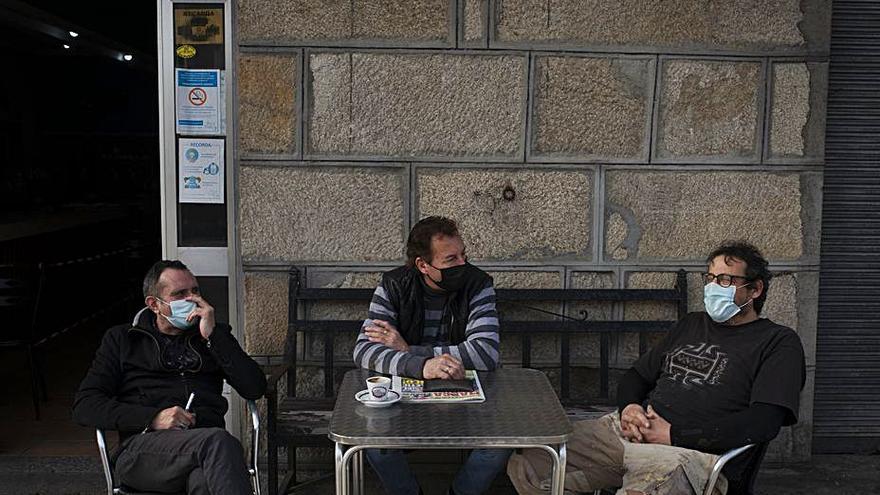 Tres hombres en una terraza en Boborás, antes de su cierre.