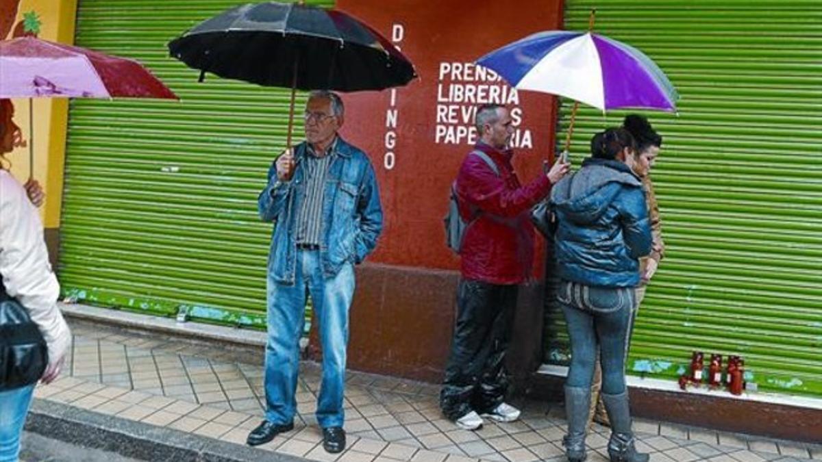 Vecinos de la víctima colocan velas ante la papelería que regentaba.