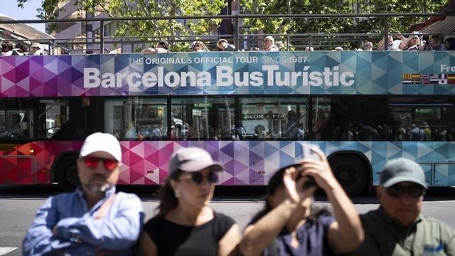 Turistes al passeig de Gràcia, amb un Barcelona Bus Turístic al darrere.