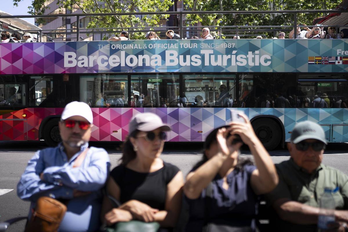 Turistas en el paseo de Gràcia, con un Barcelona Bus Turístic detrás.
