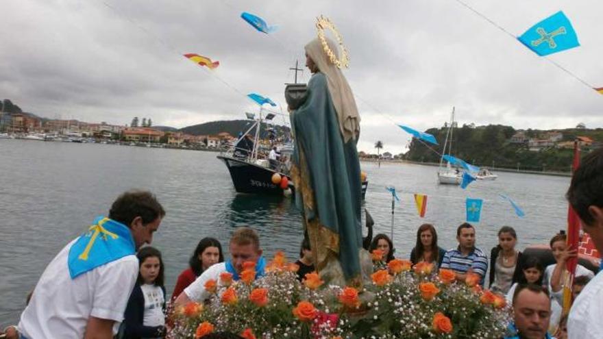 Varios marineros suben la imagen de la Virgen a la embarcación «Azkena». / emilio g. cea