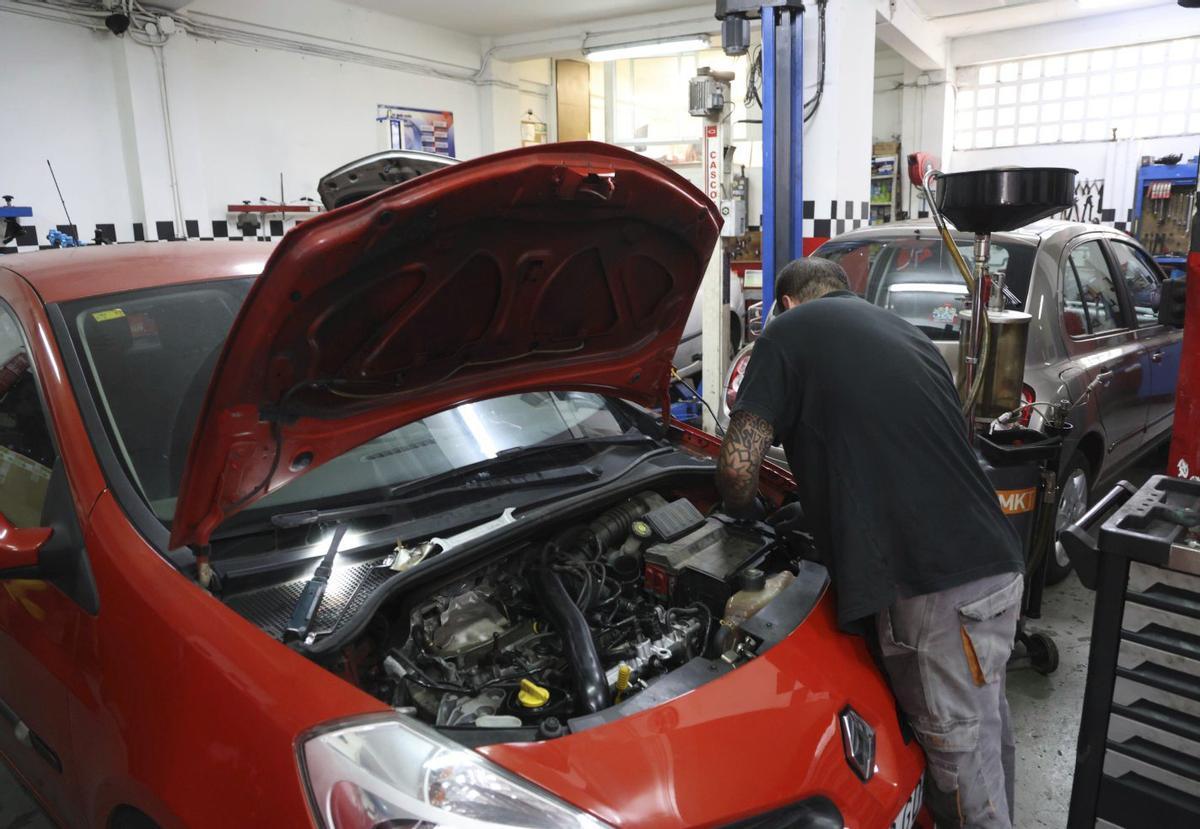 Un mecánico arregla un coche en un taller. | ALBA VILLAR