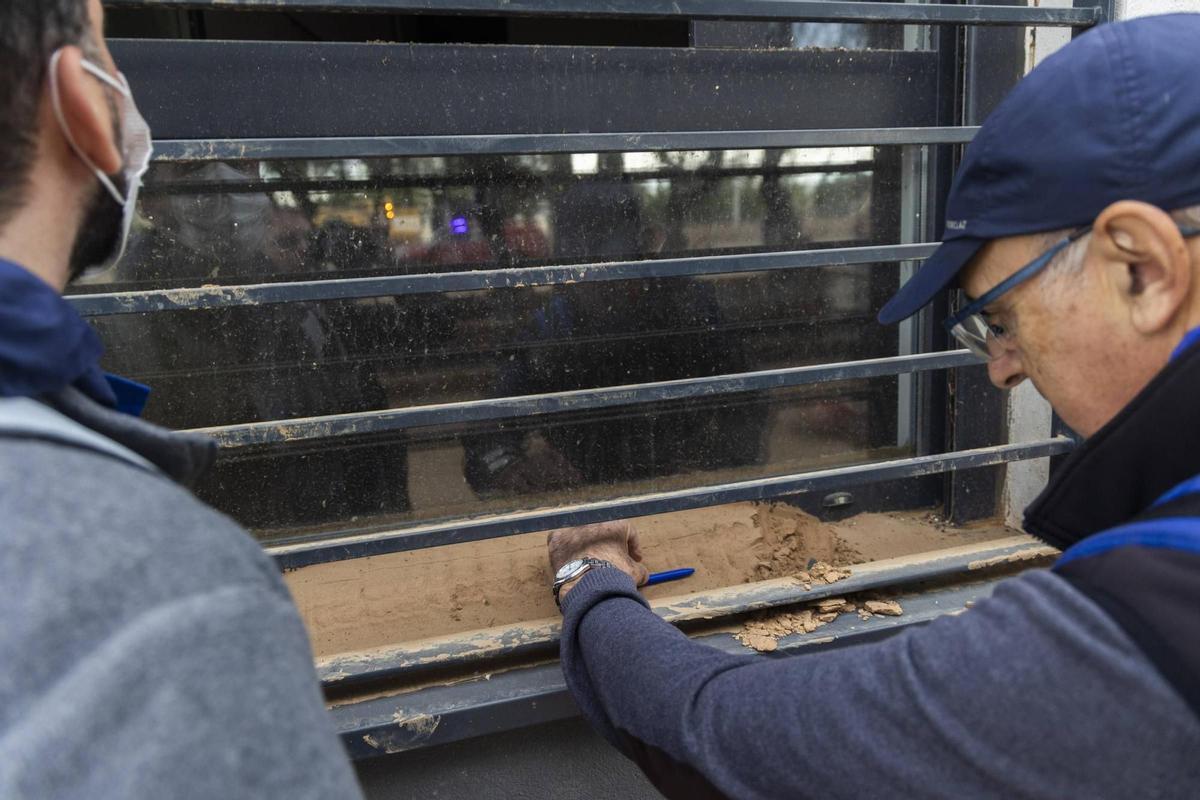 El geólogo jubilado Policarp Garay observando restos de barro en el poyo de una ventana en Paiporta.