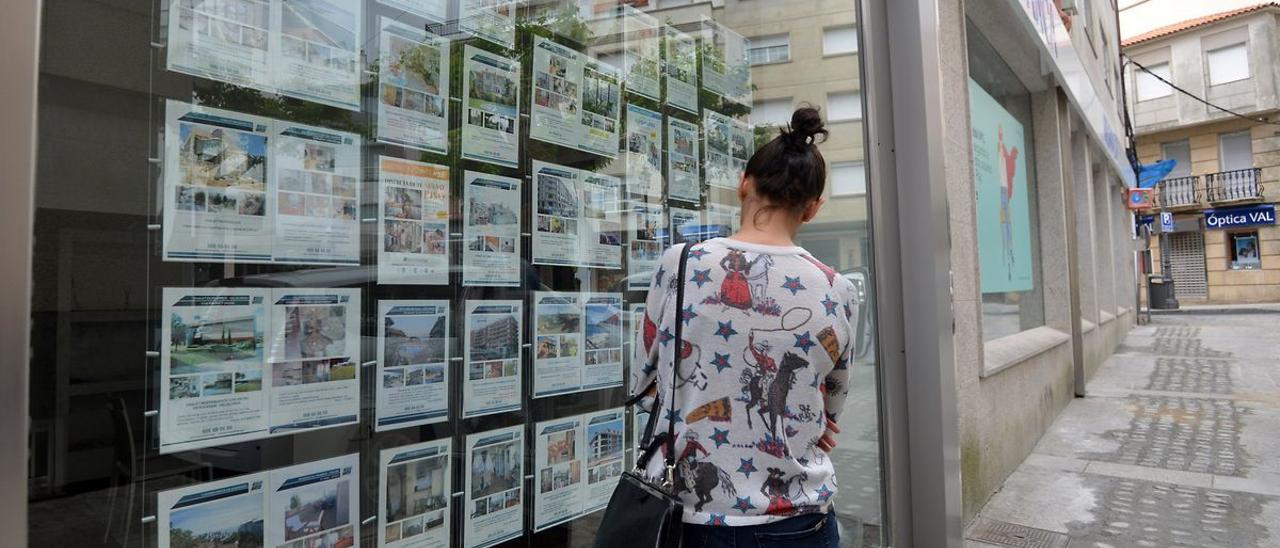 Una mujer pasa ante el escaparate de una inmobiliaria en Barcelona.