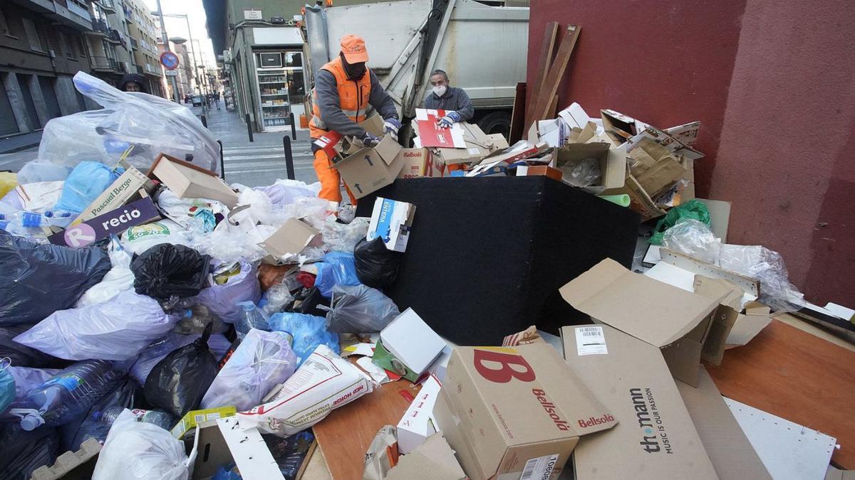 Un operari intentant recollir part del munt d’escombraries acumulades a Salt.  | MARC MARTI