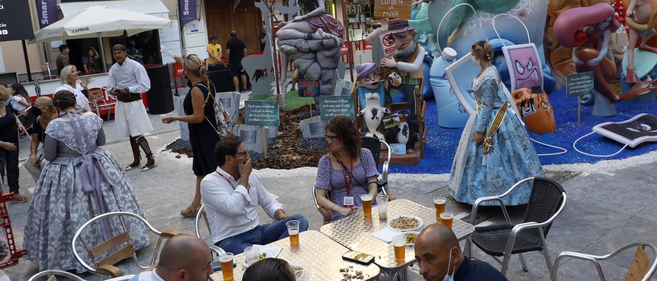 Ambiente fallero en la ciudad, con una mesa ubicada junto a un monumento.