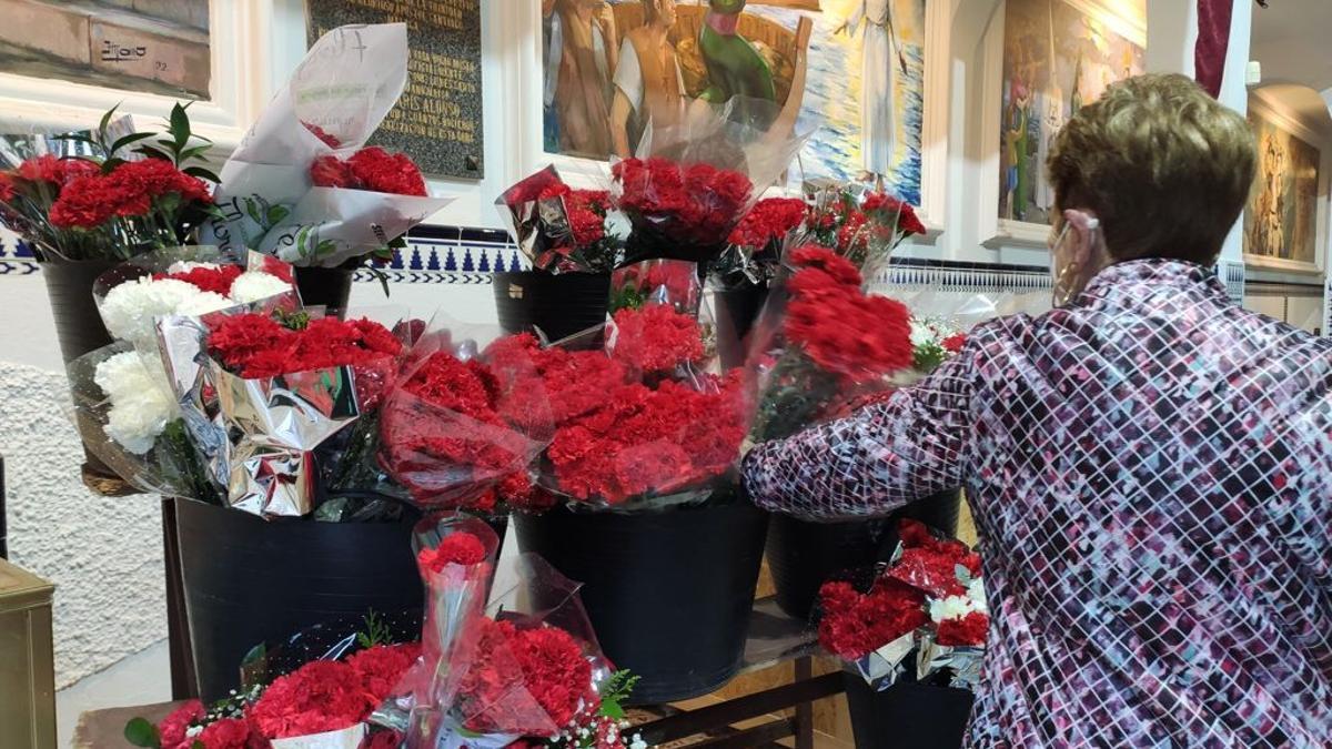 Una devota deposita claveles rojos para el trono del Cautivo.