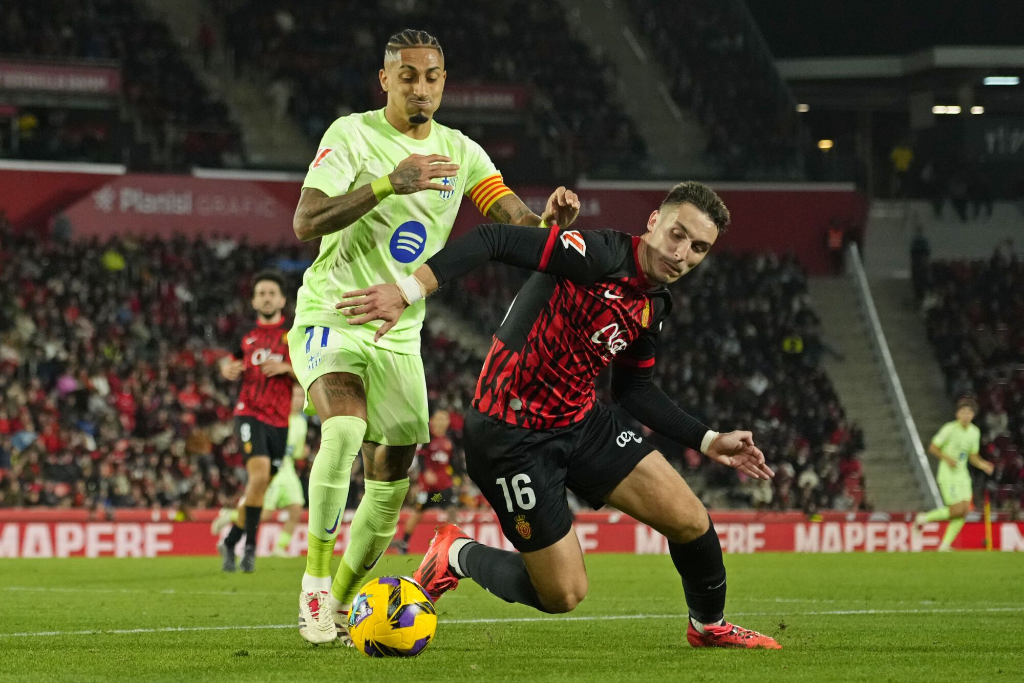 Barcelona's Raphinha, left, challenges for the ball with Mallorca's Valery Fernandez during a Spanish La Liga soccer match between Mallorca and Barcelona at the Son Moix stadium in Palma de Mallorca, Spain, Tuesday, Dec. 3, 2024. (AP Photo/Jose Breton). EDITORIAL USE ONLY / ONLY ITALY AND SPAIN