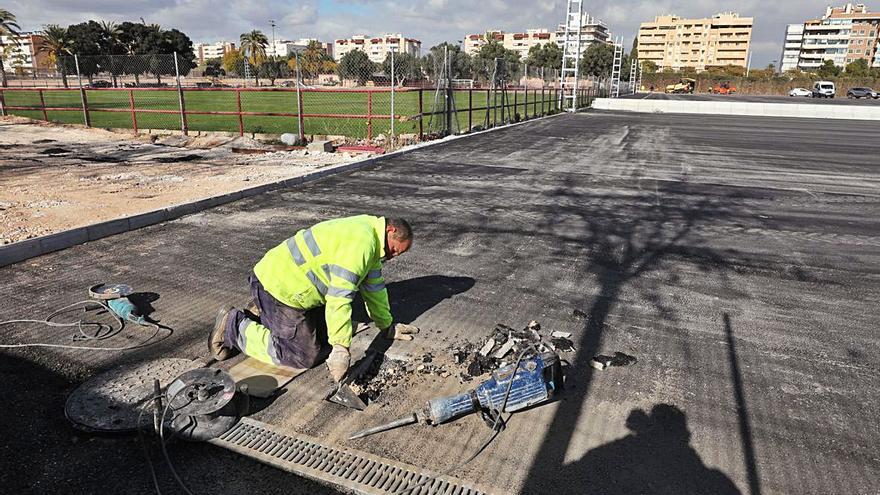 Operarios trabajando esta semana en el polideportivo en el asfaltado y la instalación de columnas de iluminación.  | ANTONIO AMORÓS