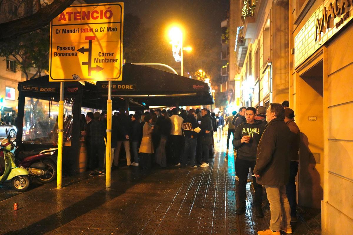 Jóvenes en la calle Mandri bajo la lluvia en la concentración del famoso botellón de Navidad