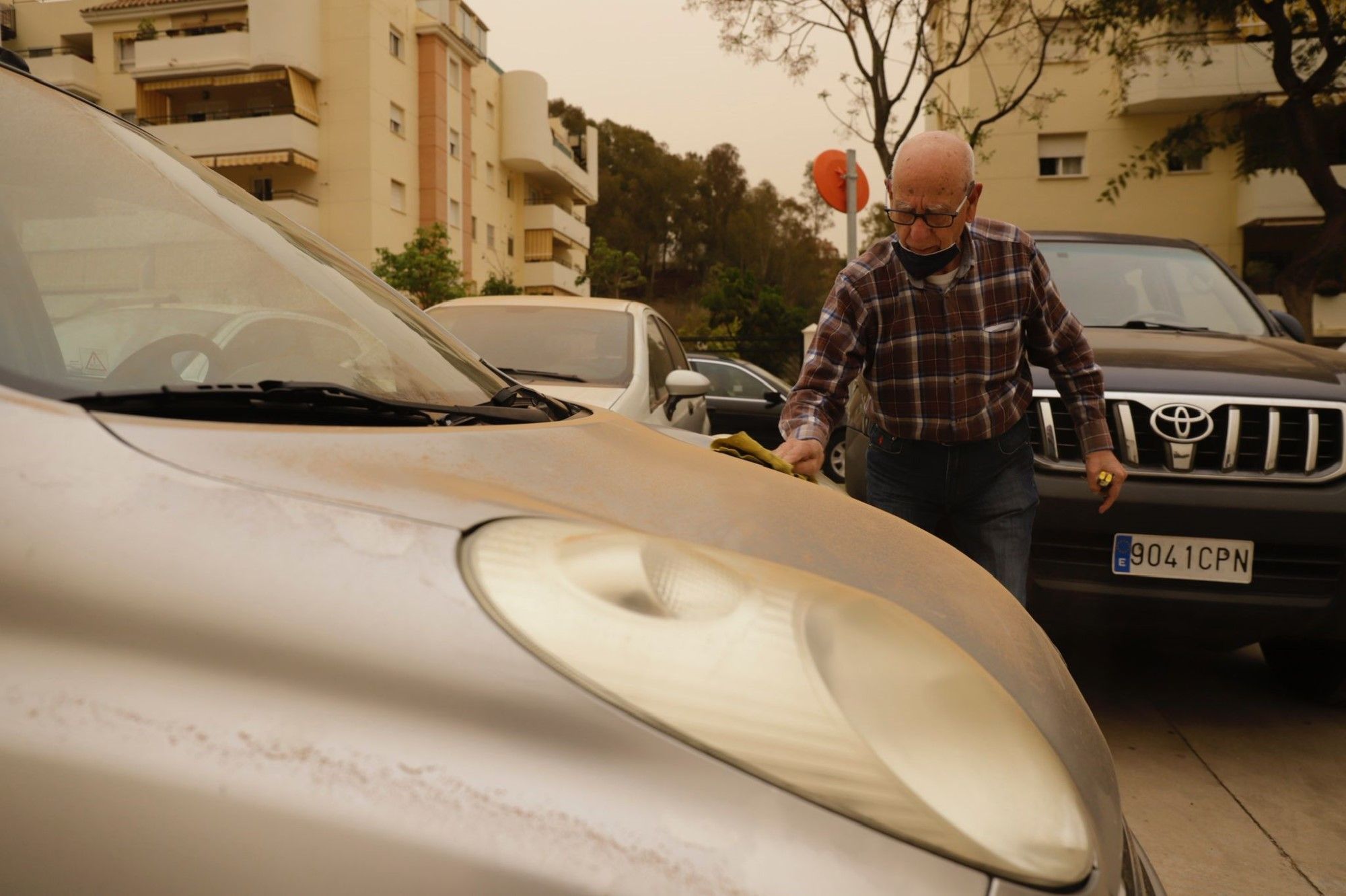 La calima deja el cielo de Málaga de color naranja y los coches llenos de polvo