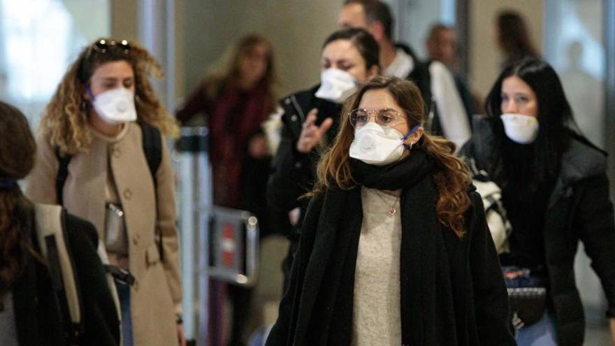 Viajeros procedentes de Italia protegidos con mascarillas a su llegada al aeropuerto de Manises.