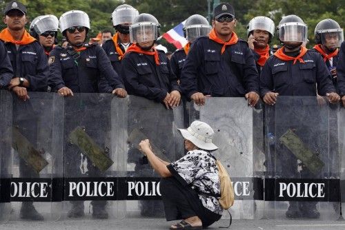 Una mujer toma fotos a una línea de policías que bloquea el paso de manifestantes que protestan por una ley de amnistía en Bangkok.