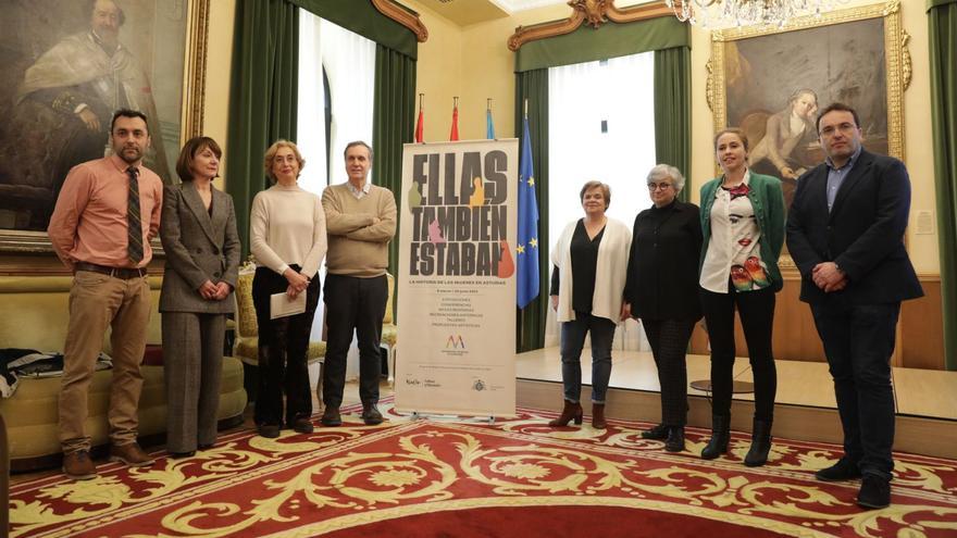 Por la izquierda, Fernando Rodríguez del Cueto, Nuria Varela, Lucía Peláez, Juaco López, Paloma García, Ana González, Carla Rubiera y Manuel Ángel Vallian, ayer, posando con el cartel de «Ellas también estaban» en el salón de recepciones del Ayuntamiento. | Juan Plaza