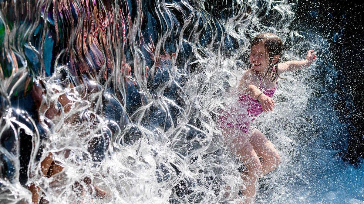 Una nena es refresca en una cascada d&#039;aigua en un parc a Washington DC.