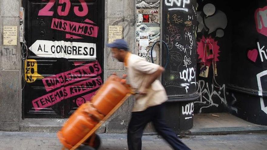 Un repartidor carga con varias bombonas de butano.