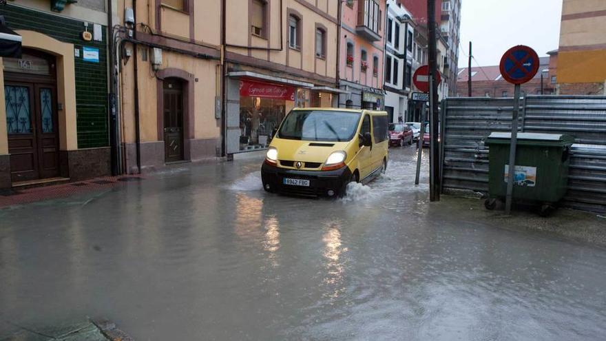 Un coche circula por la calle Julián Duro de La Felguera tras una jornada de intensas lluvias.