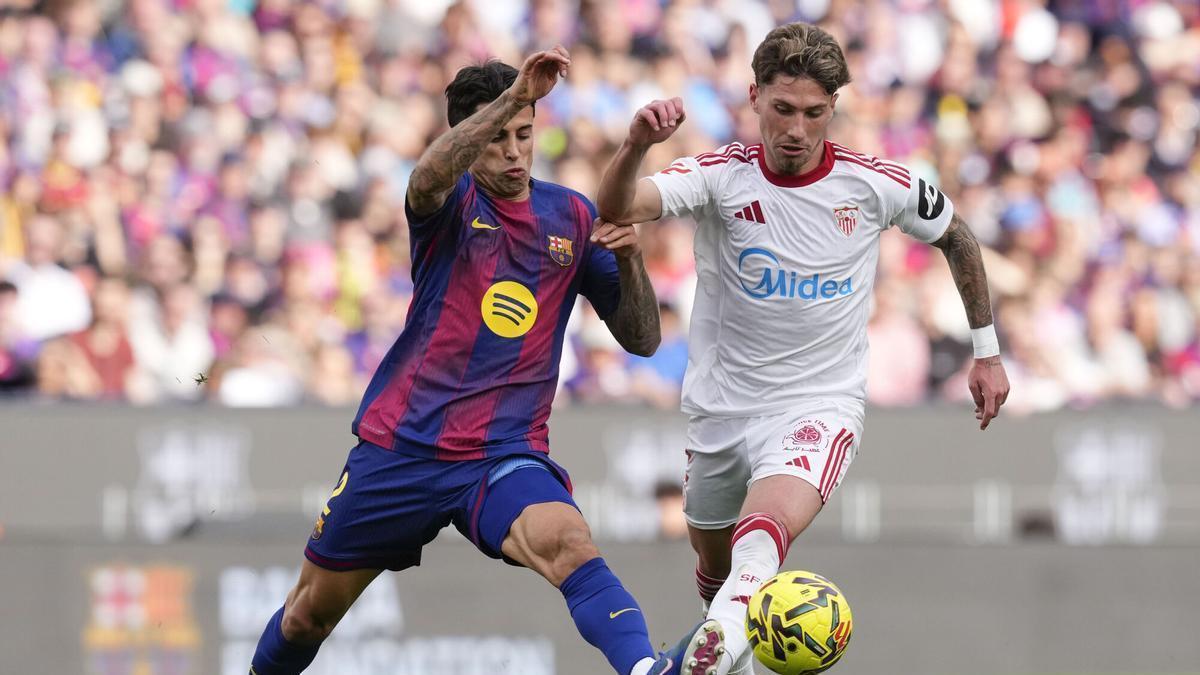 BARCELONA, 15/03/2026.- El defensa del FC Barcelona João Cancelo (i) pelea una posesión ante Carmona, del Sevilla, durante el partido de LaLiga entre el Barcelona y el Sevilla disputado en el Camp Nou en Barcelona, este domingo. EFE/ Enric Fontcuberta
