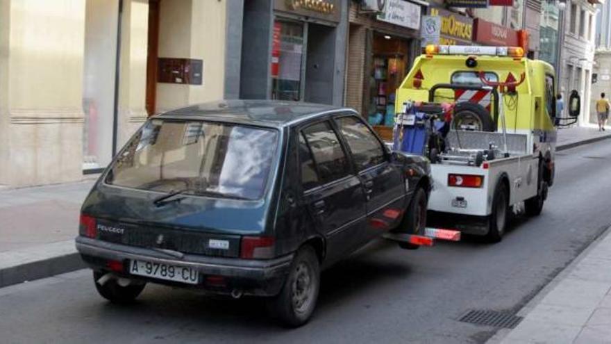 Una grúa que acaba de retirar un coche, a su paso por el centro de Elche y, concretamente, por la Corredera.