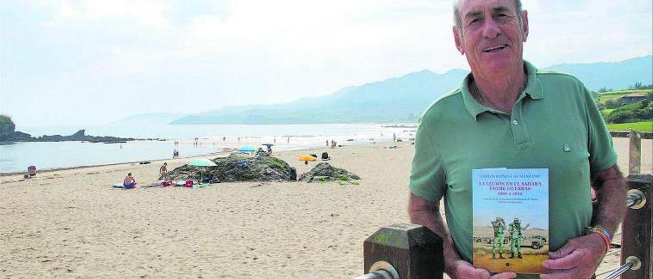 Carlos Blond, en la playa de La Isla, con su libro.