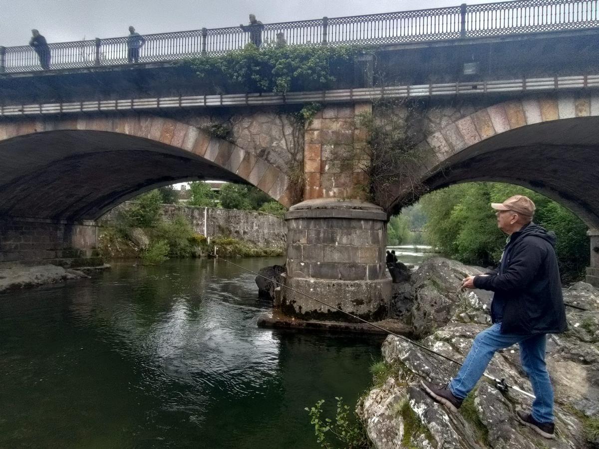 Pescador en el puente romano con curiosos observando