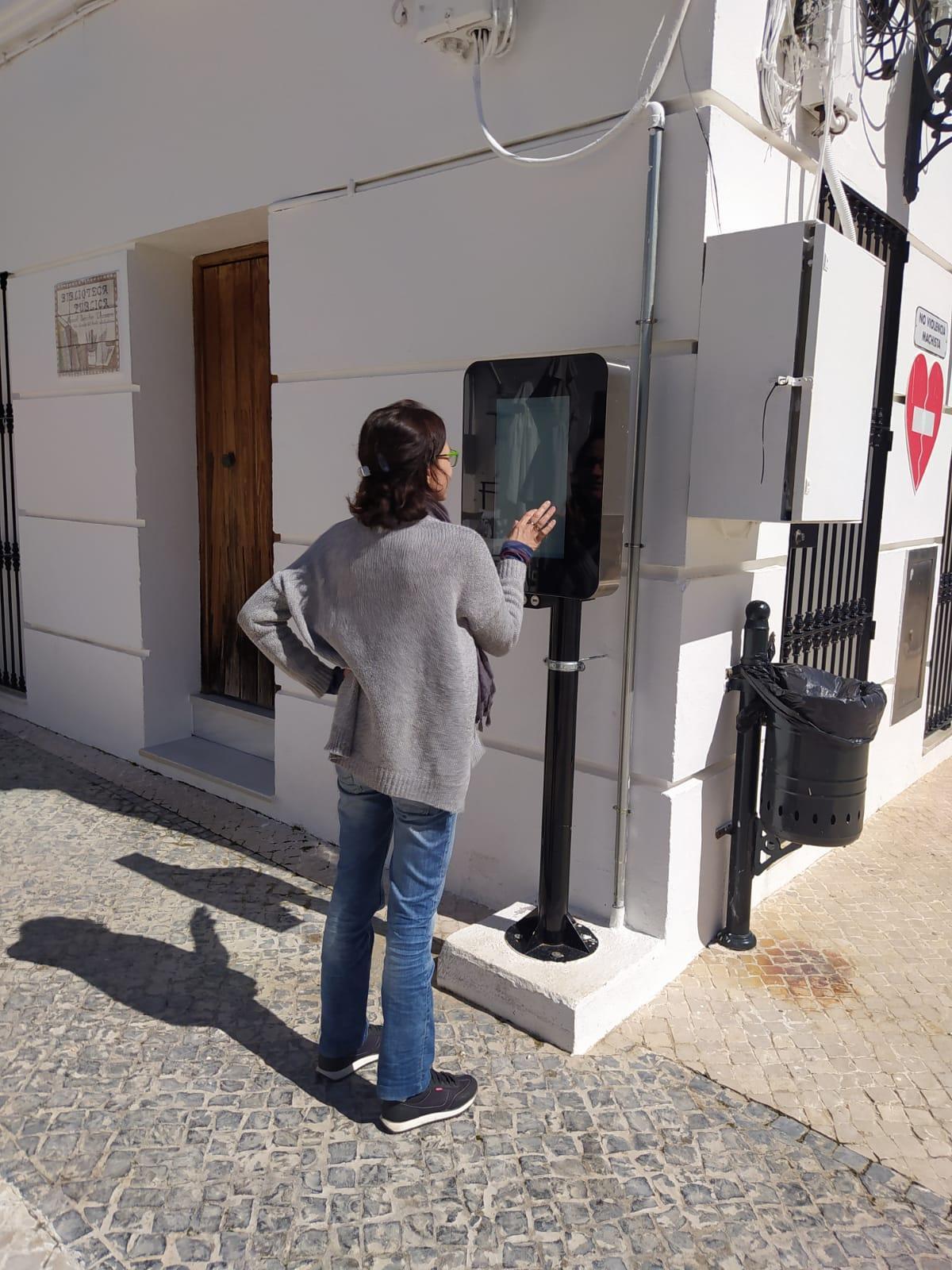 Una usuaria consulta una de las pantallas instaladas en la plaza de San Nicolás del Puerto.