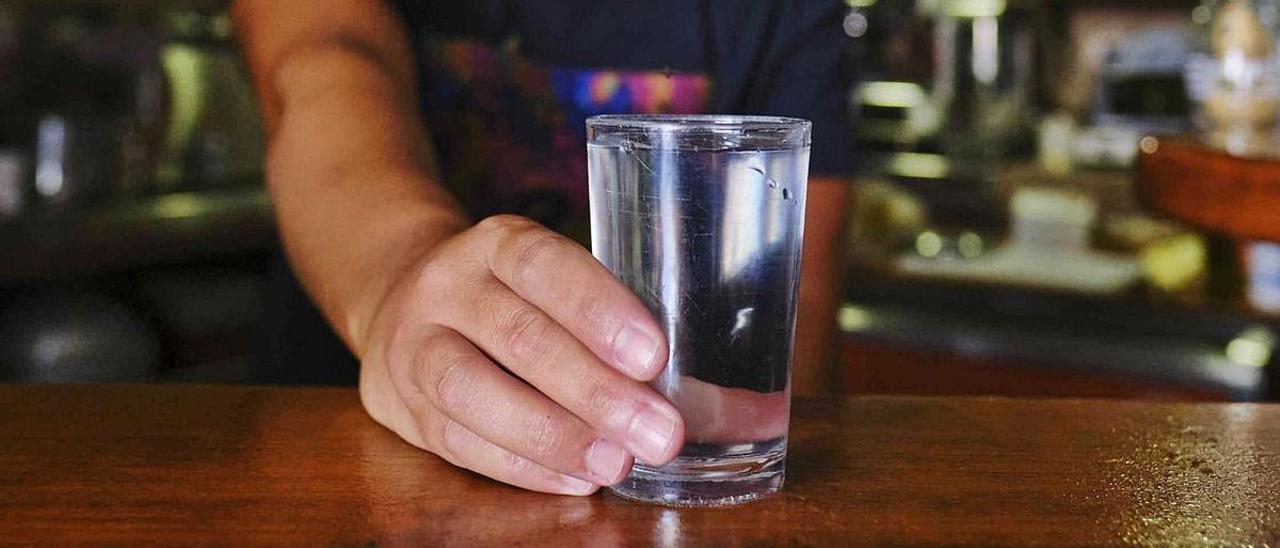 Un camarero pone un vaso de agua en un bar de La Guancha