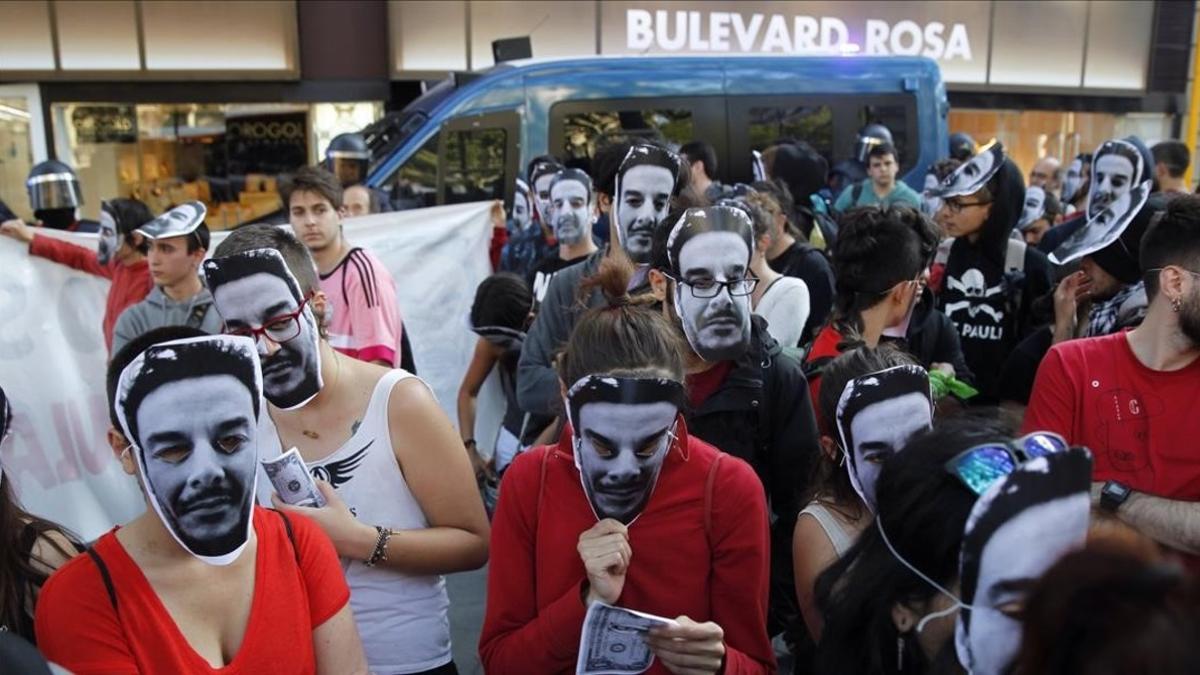 Miembros del colectivo del 'banco expropiado', con caretas del dueño del local, el jueves en el paseo de Gracia.