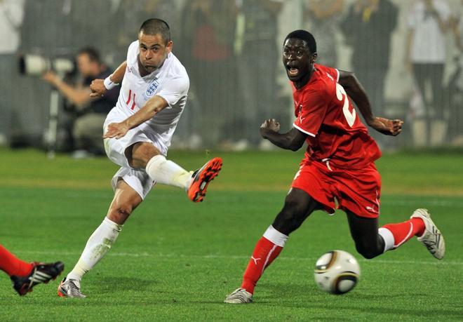 Joe Cole (L) chuta la pelota mientras Tshiamo Seneo (R), jugador del equipo local sudafricano Platinum Stars FC, durante un partido de entrenamiento público en el estadio Moruleng cerca de Rustenburg.