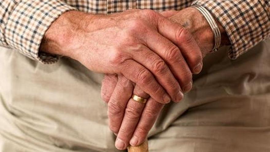 Un hombre anciano sujeta un bastón. // Pexels