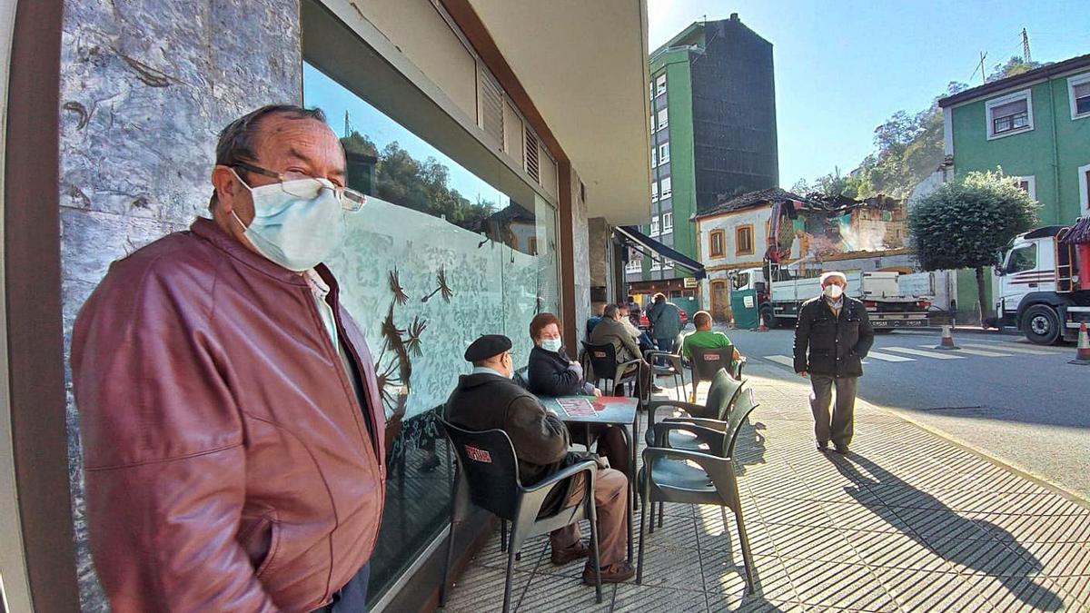 Vecinos en una terraza hostelera desde donde se ven los trabajos de demolición. | E. P.