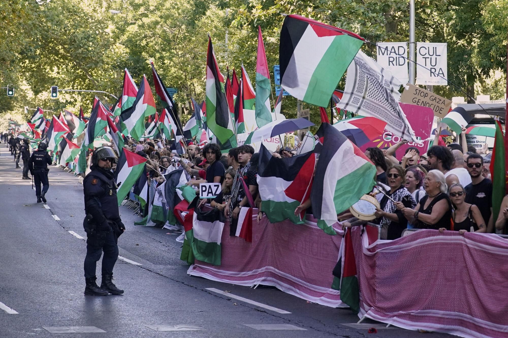 People shout slogans and hold Palestinian flags while protesting during the twenty-first stage of La Vuelta cycling race from Alalpardo to Madrid, Spain, Sunday, Sept. 14, 2025. (AP Photo/Andrea Comas)