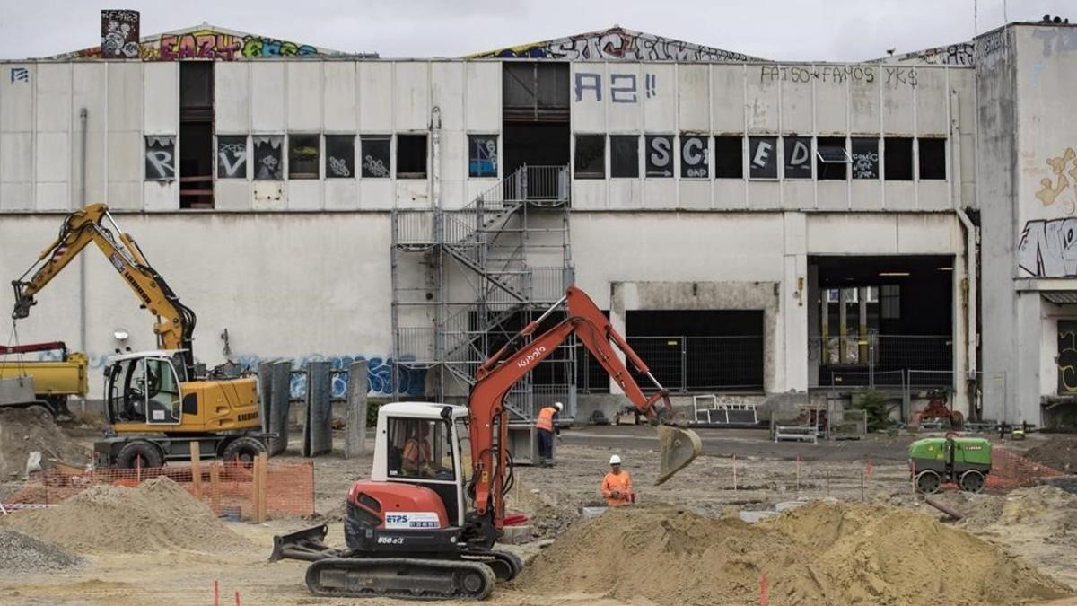 Empleados de la construcción realizan su trabajo en una estación de trenes abandonada para acondicionarla como el primer campo de refugiados de París, este martes.