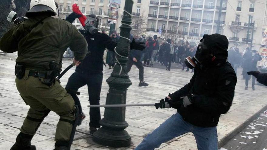 Manifestantes radicales se enfrentan a un policía antidisturbios tras la manifestación de Atenas.