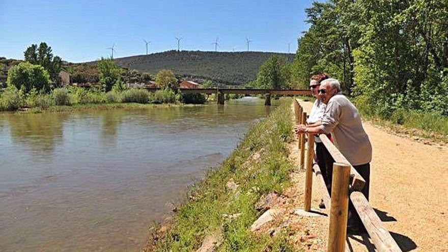 Dos personas miran el río Eria en el paseo ribereño de Villaferrueña.