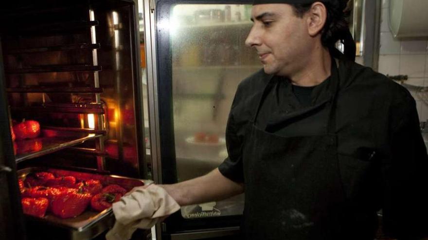 El cocinero Adolfo Fernández prepara pimientos rellenos en una sidrería de Blimea.