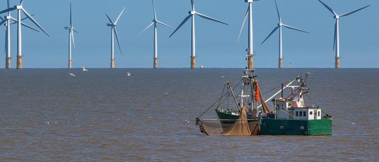 Un barco de pesca del norte de
Europa con varios molinos al 
fondo.   | // WINDEUROPE